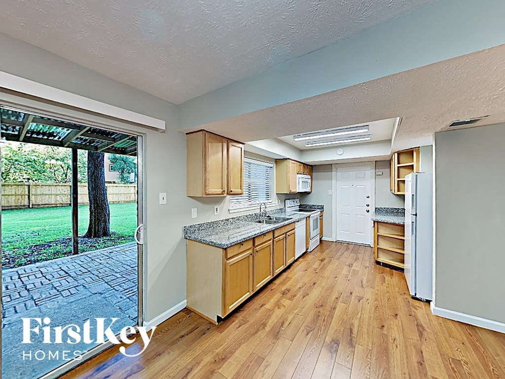 a kitchen with a wood floor and a door to a yard