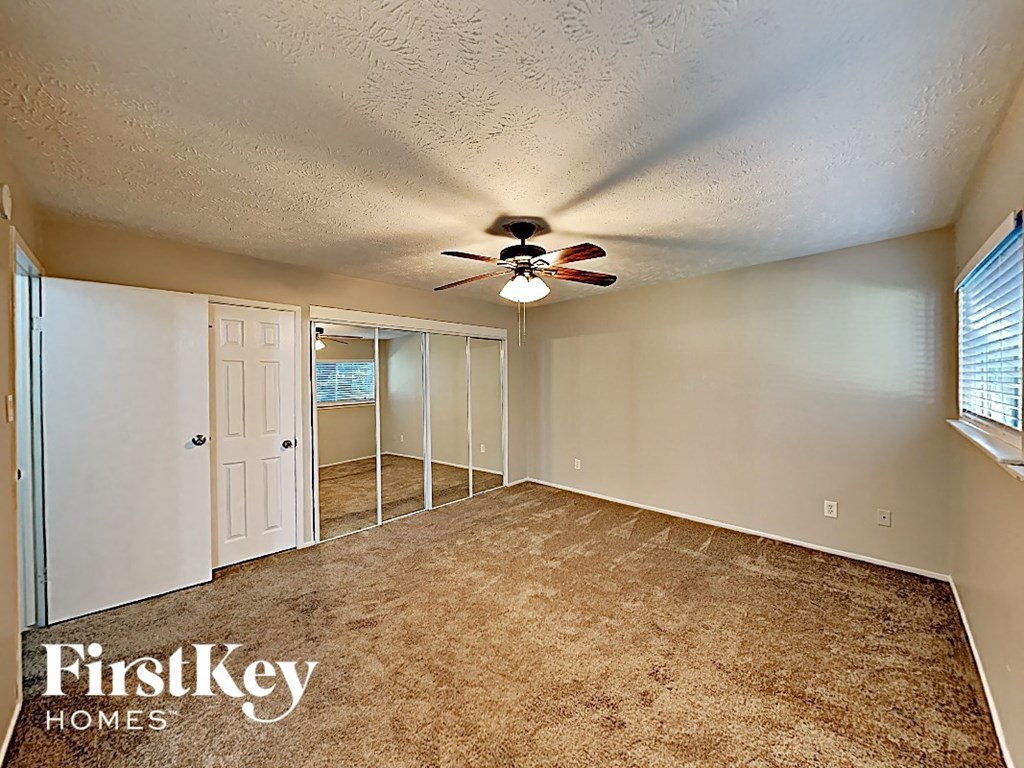 an empty bedroom with a ceiling fan and a closet