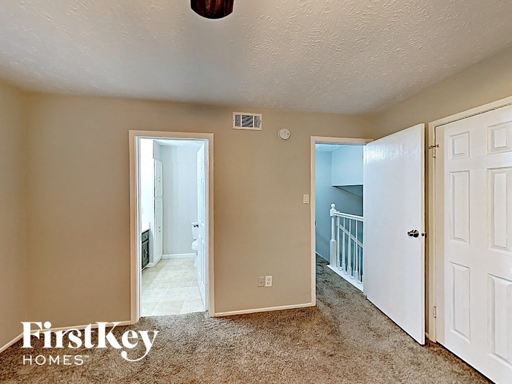 the master bedroom has a carpeted floor and a door to the hallway