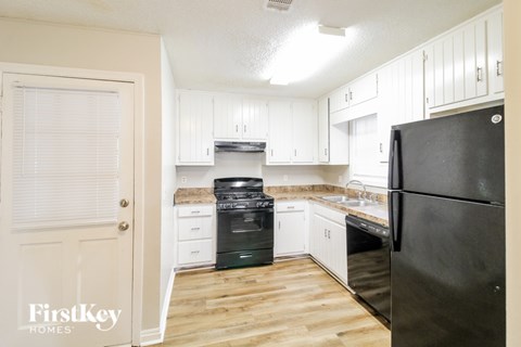 A kitchen with a black fridge and white cabinets.