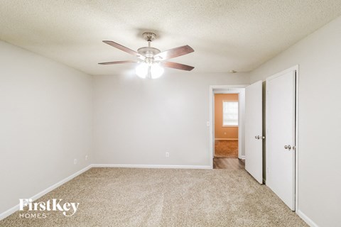 A spacious room with a ceiling fan and carpeted floor.