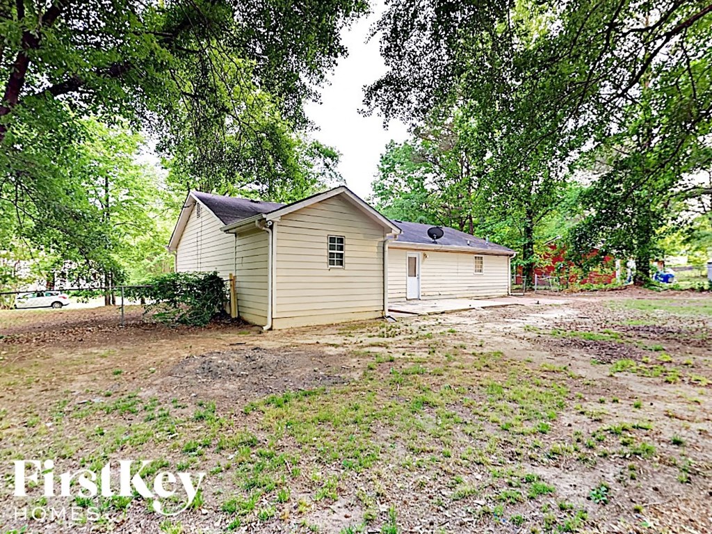 A small house with a porch is surrounded by trees.