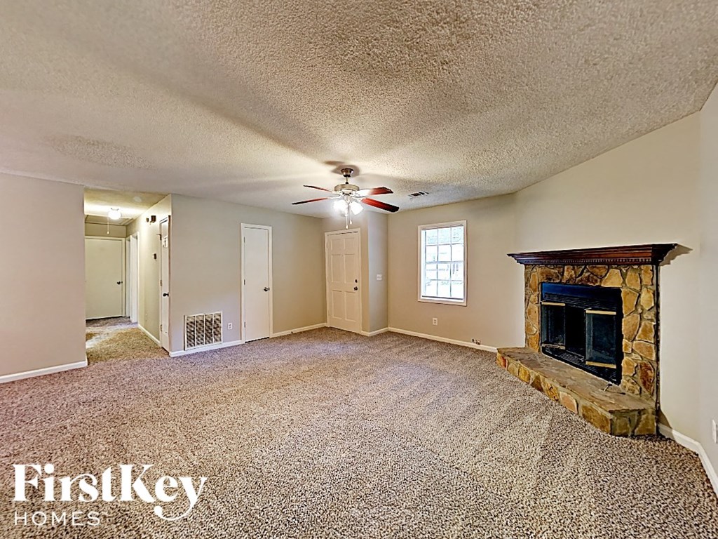 A spacious living room with a fireplace and a ceiling fan.