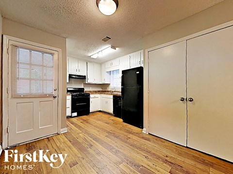 A kitchen with wooden floors and white cabinets.