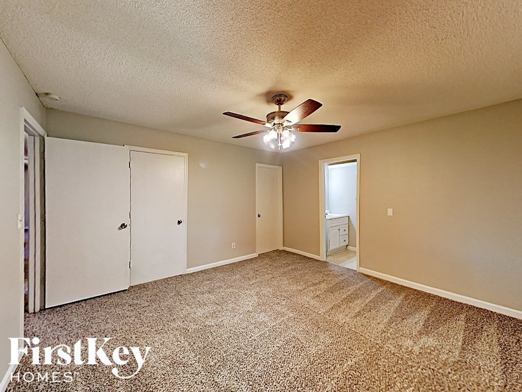 A room with a carpeted floor and a ceiling fan.