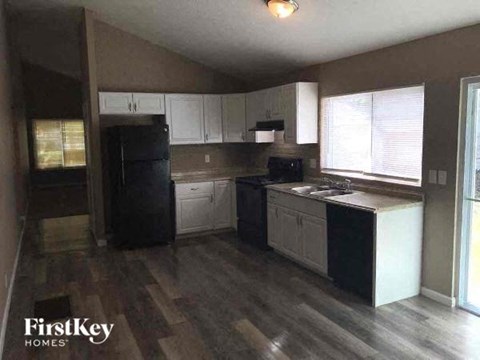 A kitchen with a black refrigerator and white cabinets.