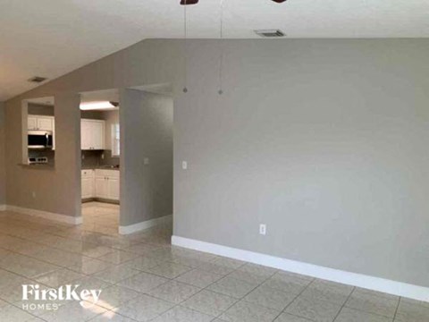an empty living room and kitchen with a tile floor