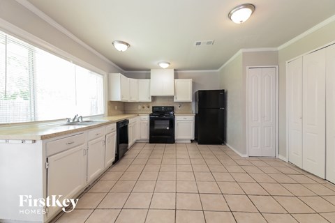 A kitchen with white cabinets and black appliances.