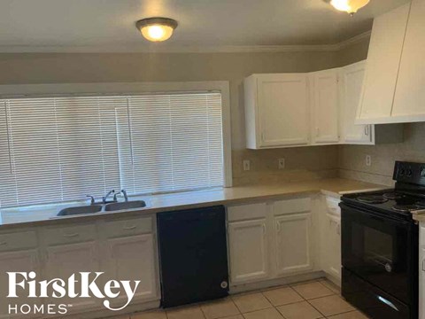 a kitchen with white cabinets and a sink and a window