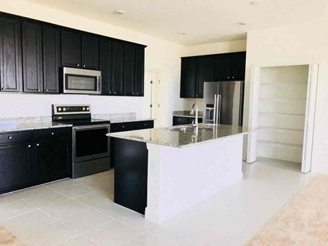 A kitchen with black cabinets and a white island.