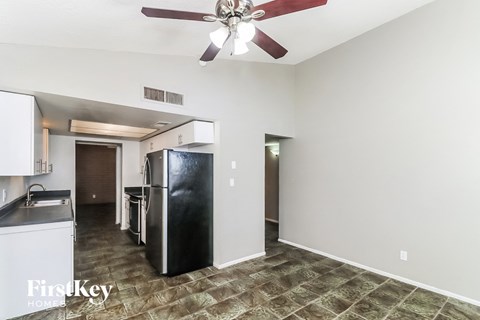 A kitchen with a black fridge and a ceiling fan.
