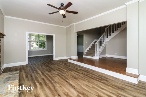 A spacious room with wooden floors and a staircase leading to another level.