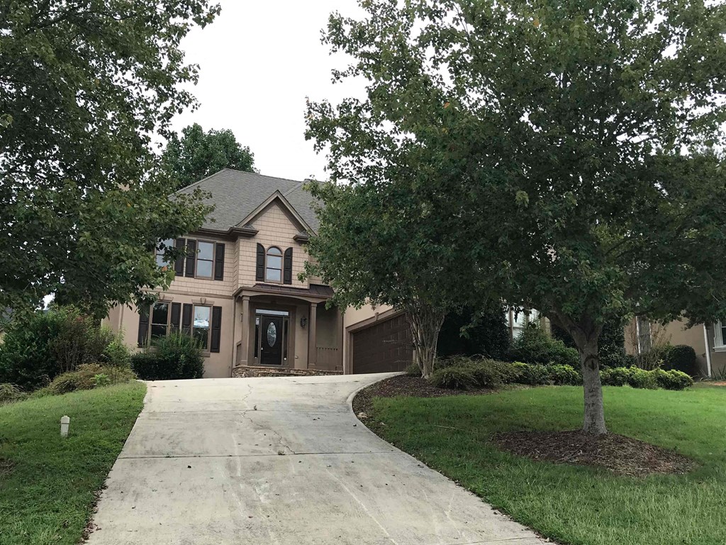 A house with a driveway and trees in front.