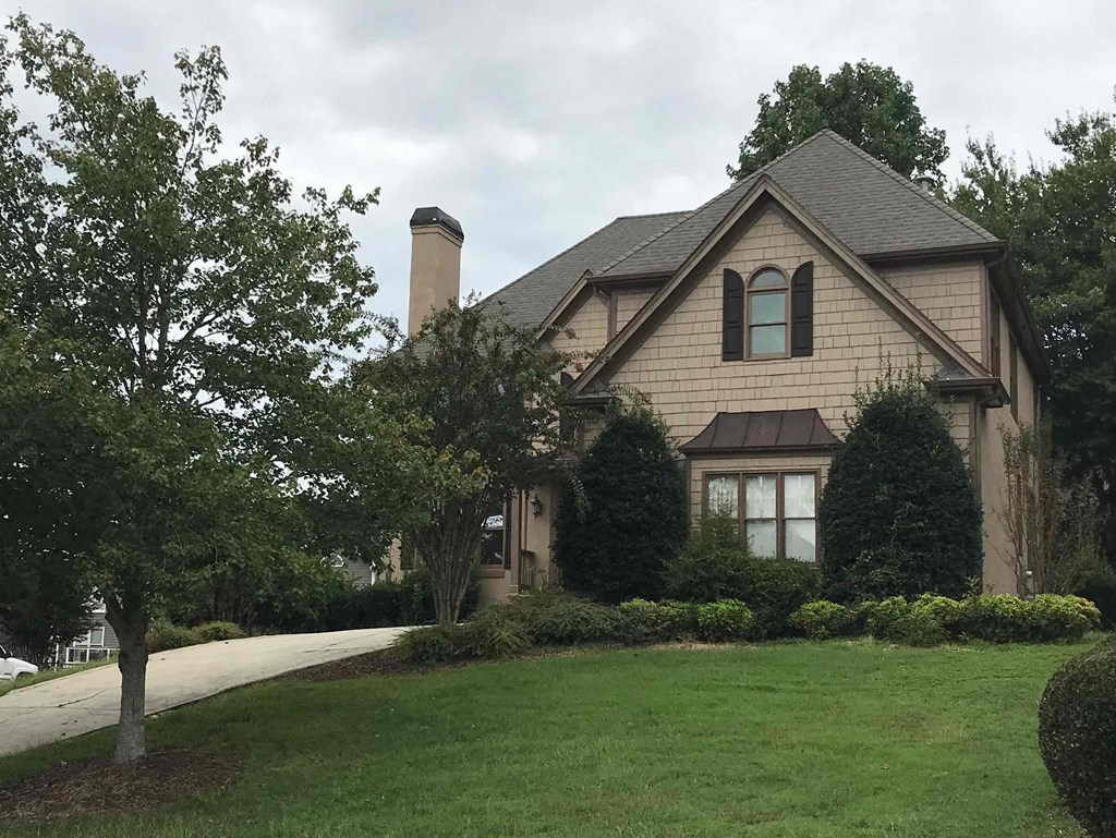 A house with a brown roof and a large front yard.