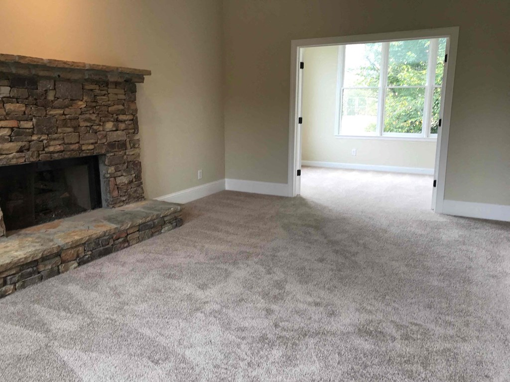 A room with a stone fireplace and carpeted floor.