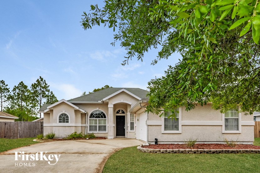 a house with a driveway and a tree in front of it