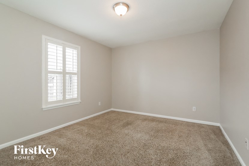 the second bedroom has a carpeted floor and a window