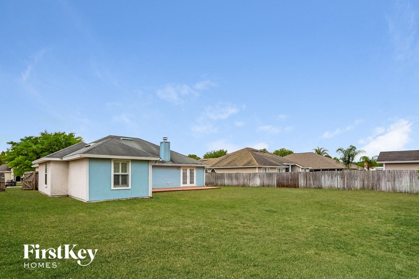 a backyard with a blue house and a fence