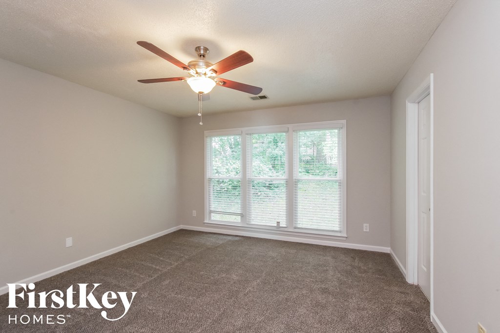 an empty living room with a ceiling fan and a large window