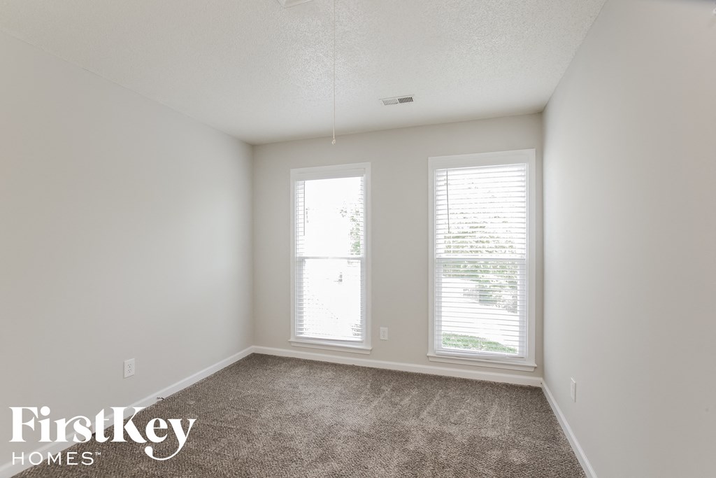 a bedroom with two windows and a carpeted floor