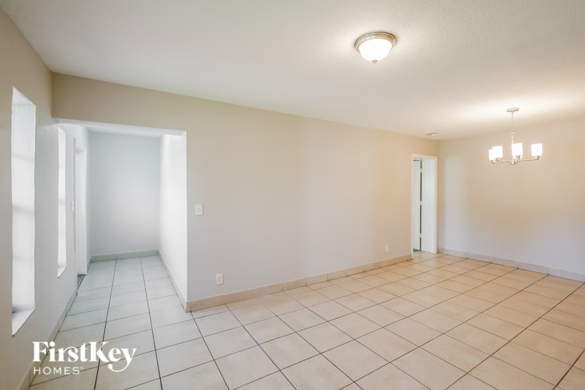 A spacious room with a tile floor and a chandelier hanging from the ceiling.