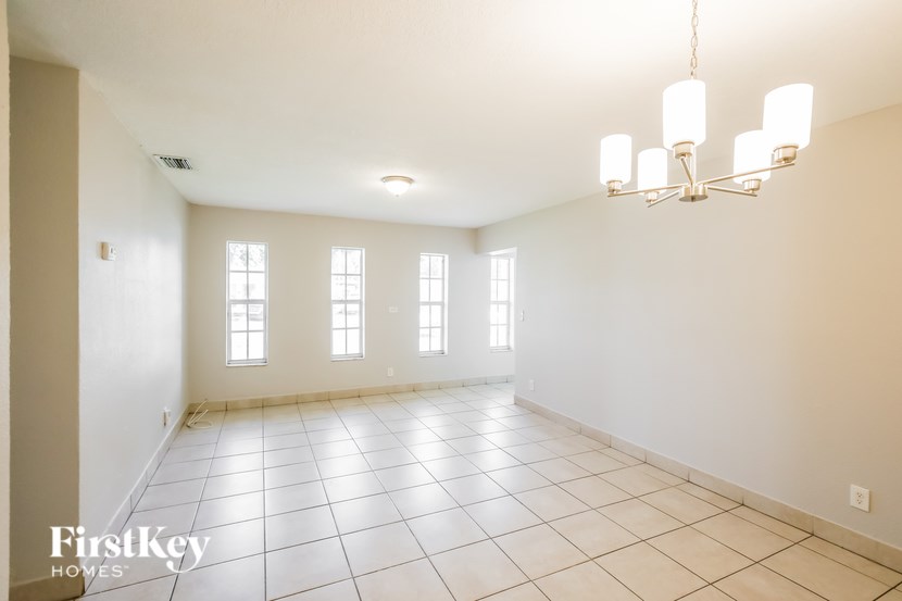 A large empty room with a chandelier and three windows.