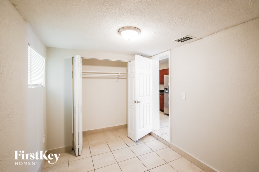 A white bedroom with a large open closet door.