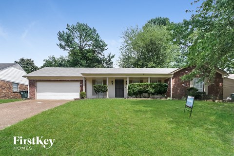 a small brick house with a lawn and a garage