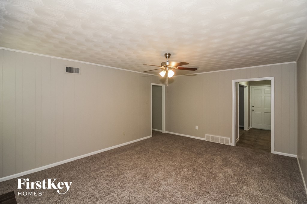 a empty living room with a ceiling fan and a door to a closet