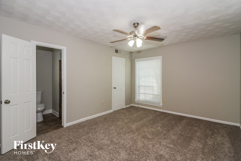 a bedroom with a ceiling fan and a door to the bathroom