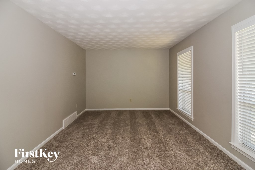a bedroom with a carpeted floor and two windows