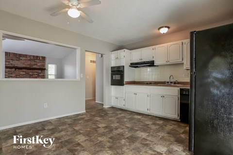 A kitchen with a black refrigerator and white cabinets.
