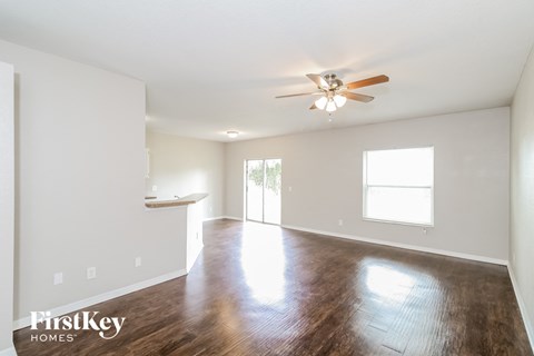 an empty living room with a ceiling fan and wood flooring