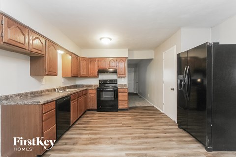 A kitchen with wooden cabinets and a black fridge.