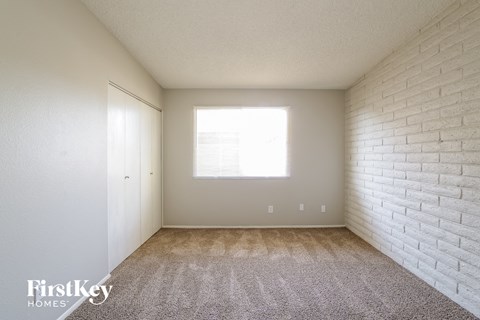 a bedroom with white brick walls and carpet and a window