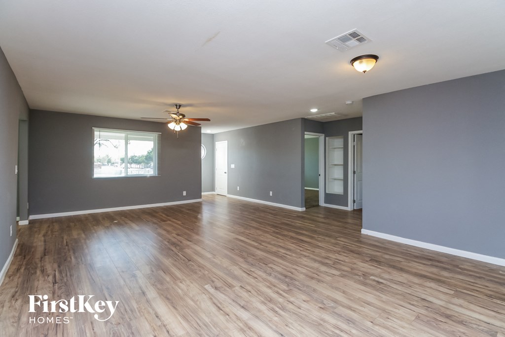 an empty living room with a ceiling fan and wood floors