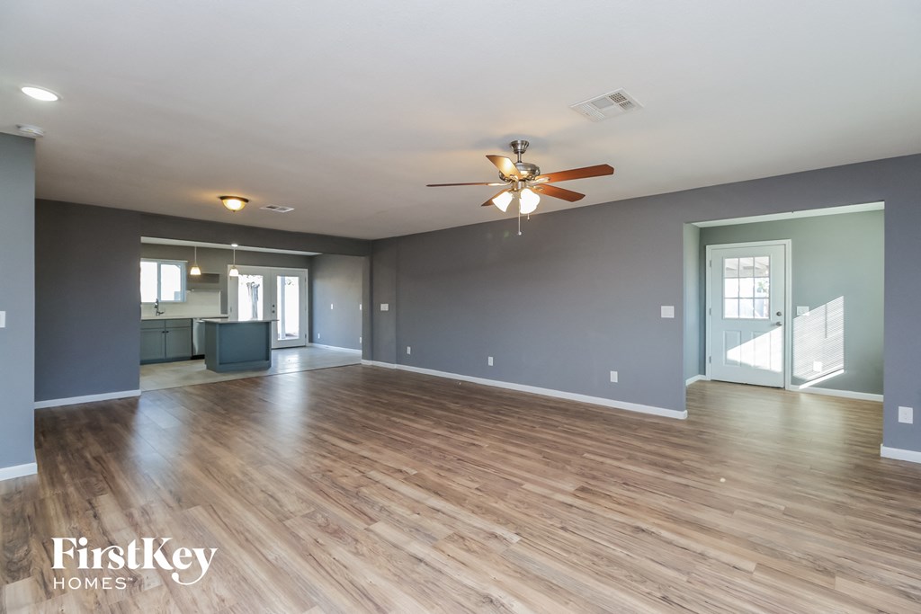 the living room and dining room with wood floors and a ceiling fan