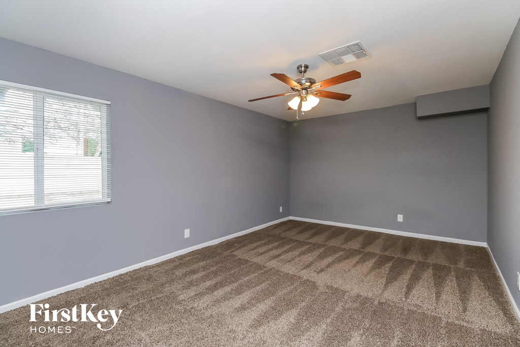 the living room of an empty house with gray walls and a ceiling fan