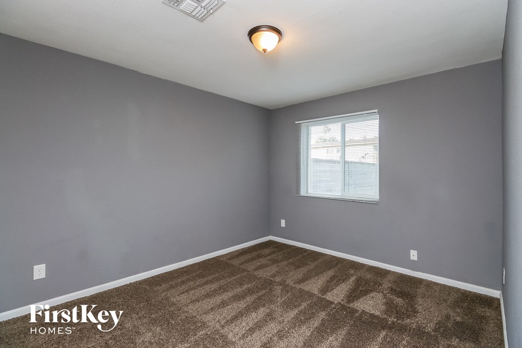 the bedroom of a house with a carpet and a window