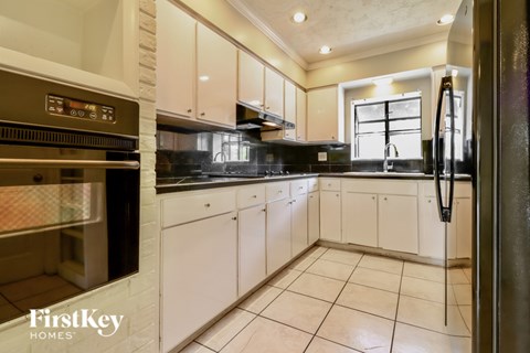 A kitchen with white cabinets and a black stove top oven.