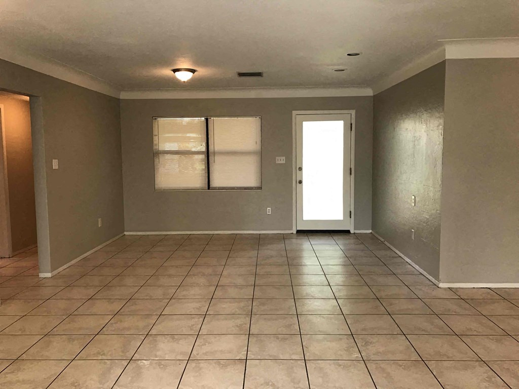 A room with tile flooring and a door leading to another room.