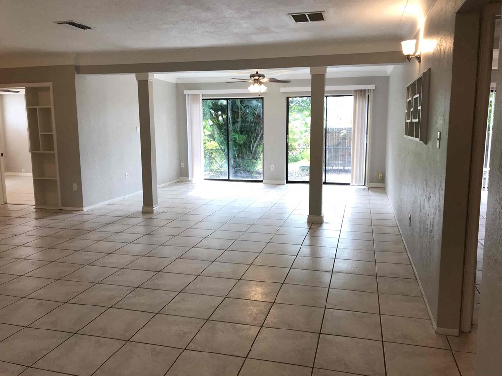 A spacious room with tiled flooring and a ceiling fan.