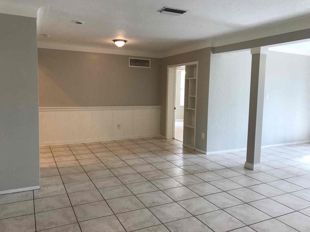 A room with tile flooring and a doorway leading to another room.