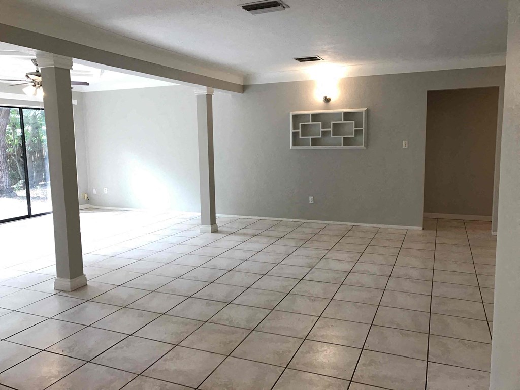 A spacious room with tiled flooring and a ceiling fan.