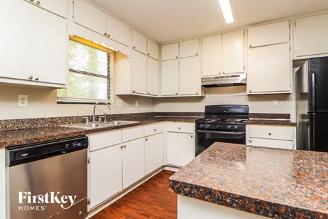 a kitchen with white cabinets and granite counter tops and black appliances