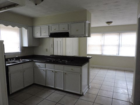 A kitchen with white cabinets and a black counter top.