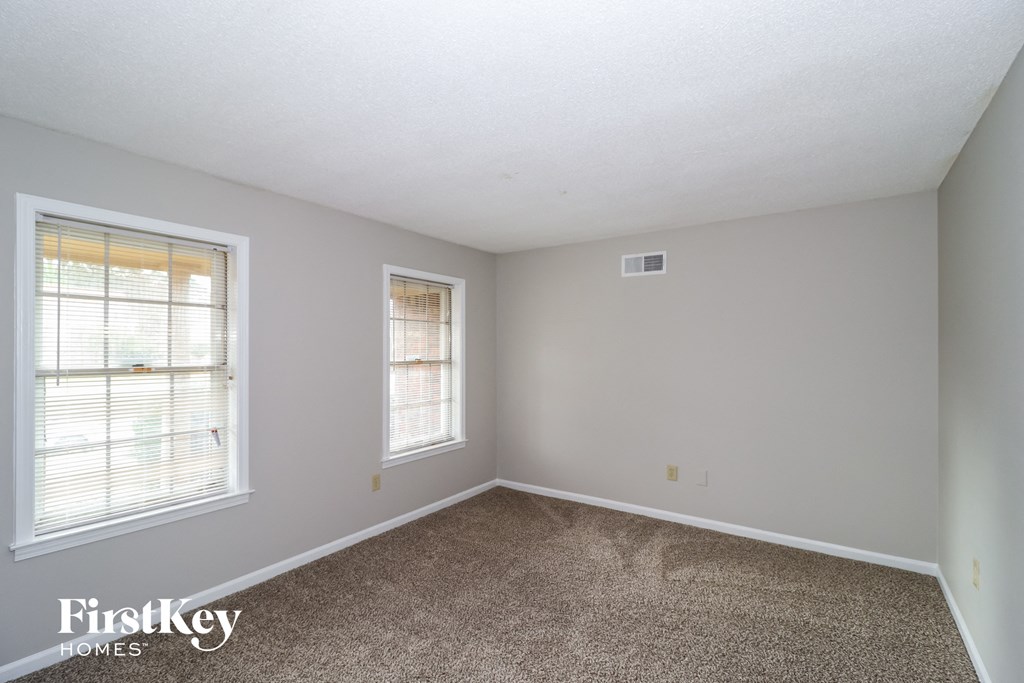 a bedroom with a carpeted floor and two windows
