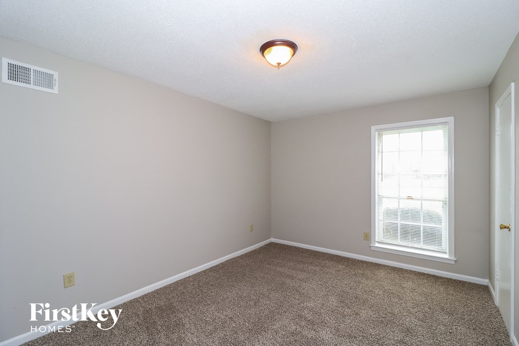 a bedroom with a carpeted floor and a window