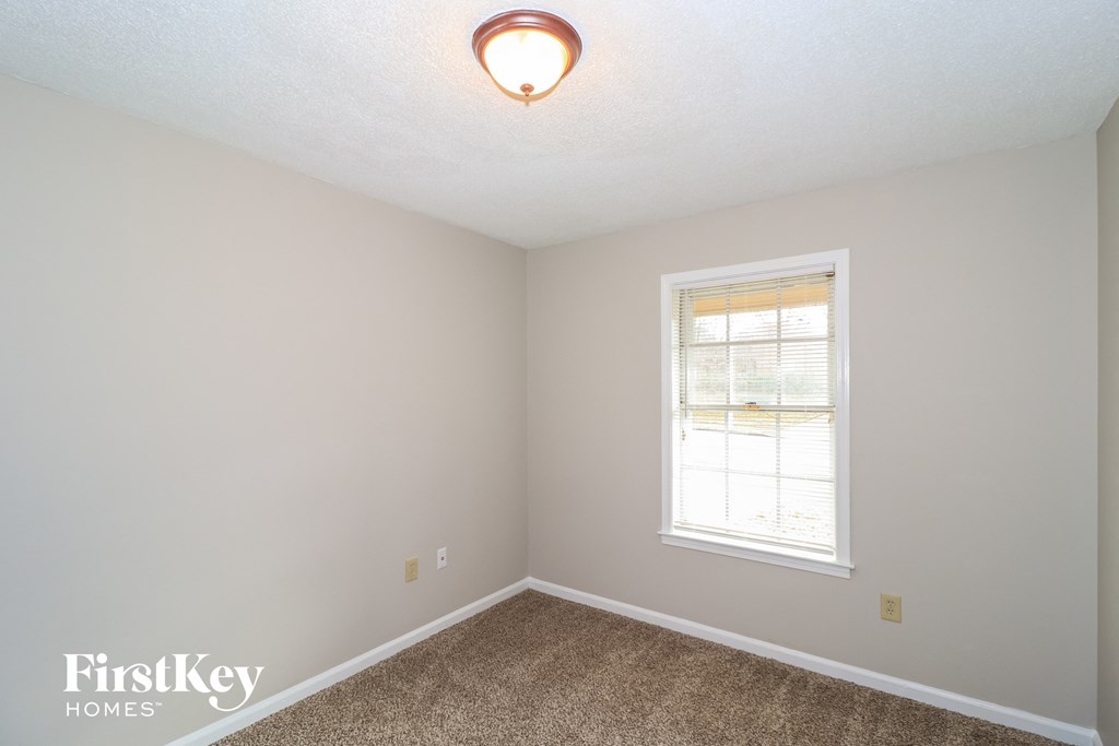 a bedroom with a window and a carpeted floor