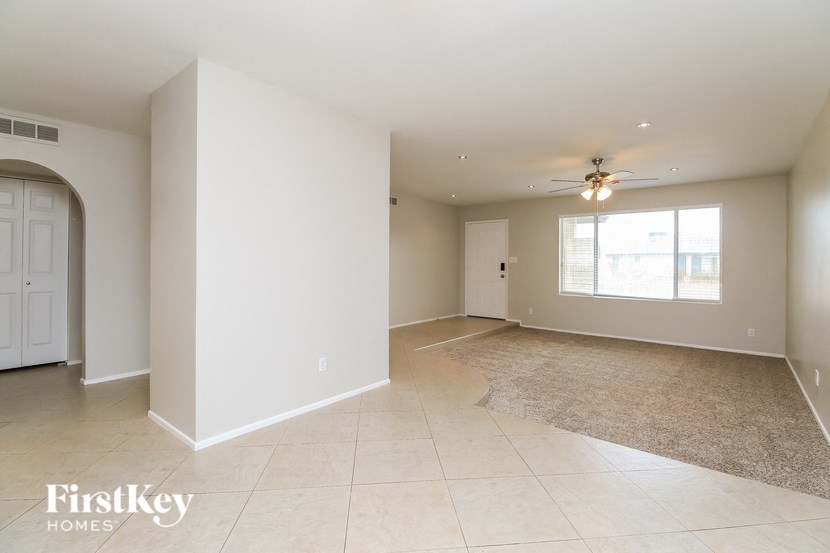 an empty living room and dining room with a ceiling fan
